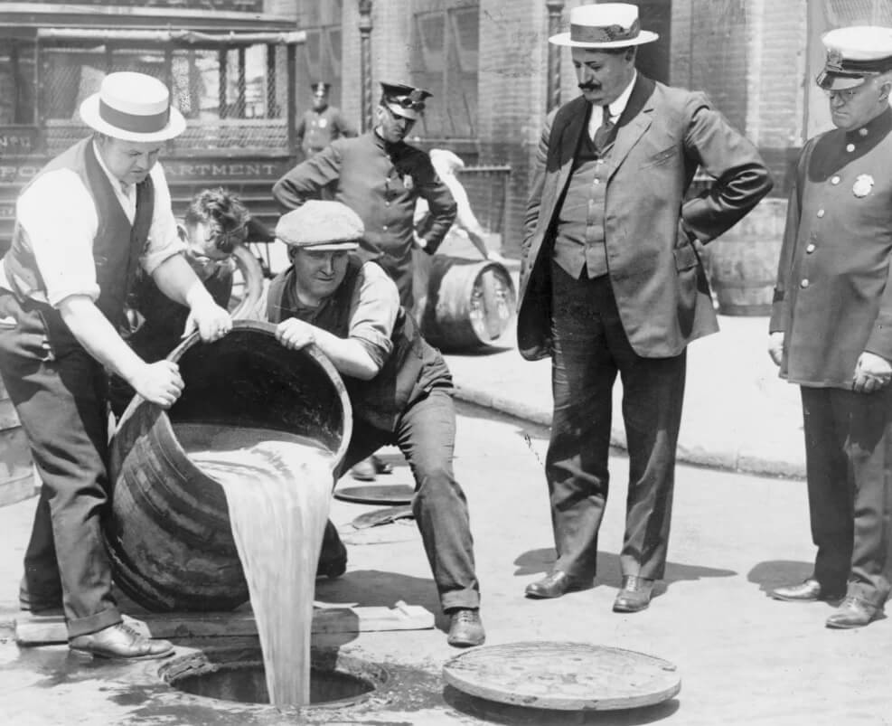 El Comisionado Adjunto de Policía de la Ciudad de Nueva York, John A. Leach (derecha), observando a los agentes verter licor en la alcantarilla tras una redada (1920). Colección de Fotografías del New York World-Telegram y el Sun Newspaper, Library of Congress, Washington, D.C.